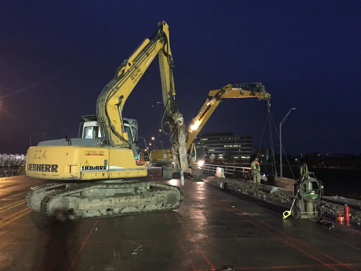 A couple of large yellow construction vehicles are on the street